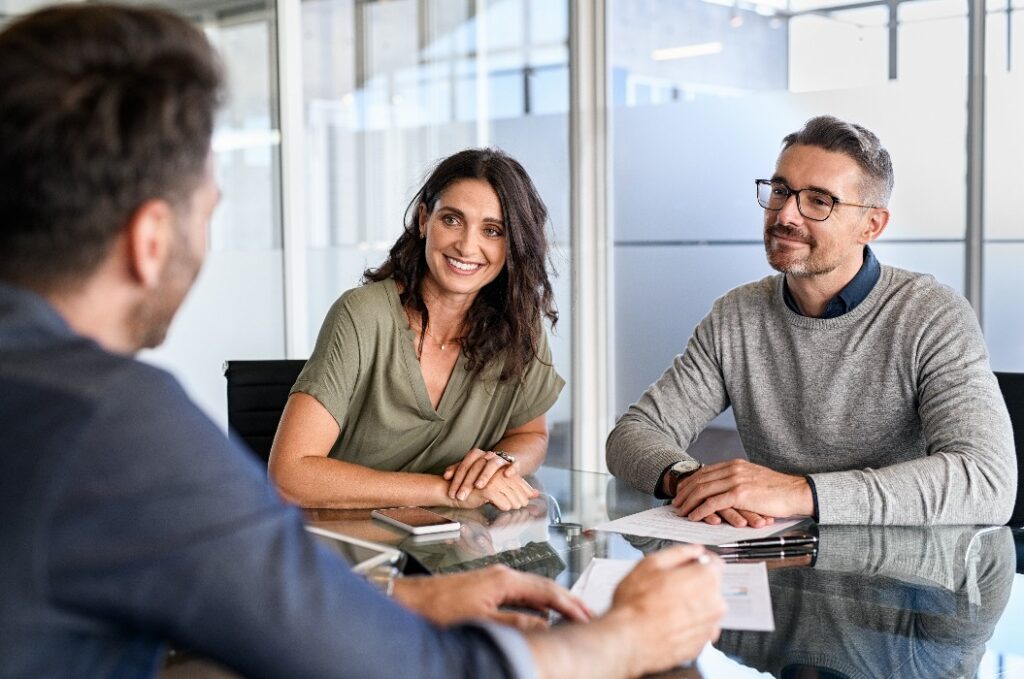 Ein älteres Ehepaar trifft sich mit einem Finanzberater, um über eine Geldanlage zu sprechen
